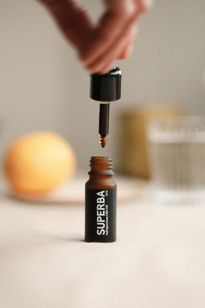 Superba elegant bottle in hand dripping oil drops of Full Spectrum CBD Oil 10% Organic And Natural Made in Italy